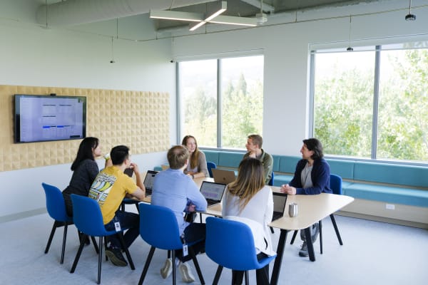 Eight 10x employees are seated at a long table in a conference room